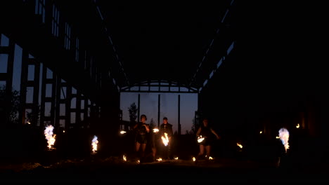 Four-women-in-leather-clothes-with-fire-dance-and-show-fire-show-a-man-with-a-flamethrower-in-the-back-plays-with-the-flame-in-slow-motion